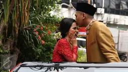 Ajie Pujien mencium kening sang istri yang juga komedian, Chika Waode saat akan meninggalkan KUA Gambir, Jakarta, Rabu (11/5). Setelah menikah, pasangan yang sudah pacaran selama 4 tahun itu akan menggelar resepsi di Padang. (Liputan6.com/Herman Zakharia)