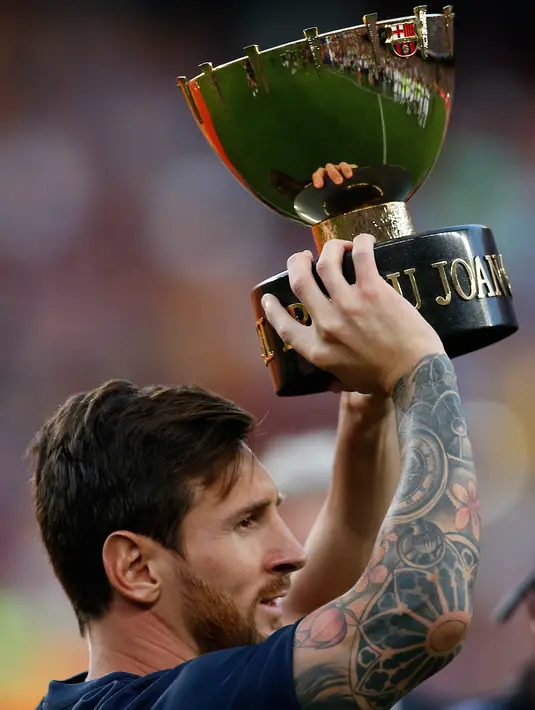 Penyerang Barcelona, Lionel Messi mengangkat Piala Joan Gamper usai pertandingan melawan Boca Juniors di stadion Camp Nou, Spanyol (15/8). Barcelona menang telak 3-0 atas Boca Juniors. (AP Photo/Manu Fernandez)