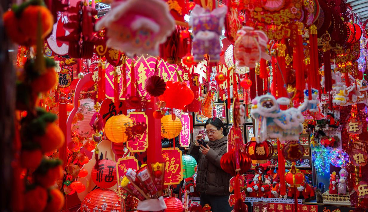 Seorang pembeli memotret dekorasi Tahun Baru Imlek di sebuah pasar di Beijing, China, Rabu 4 Februari 2026. Imlek merupakan sebuah perayaan yang sangat penting bagi masyarakat China. Perayaan tahun baru ini didasarkan oleh penanggalan lunar (bulan). (AP Photo/Vincent Thian)