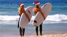  Dua wisatawan asal Jerman mengenakan topi Natal bersiap bermain surfing di Bondi Beach Sydney pada Hari Natal di Australia, (25/12). (REUTERS/David Gray)