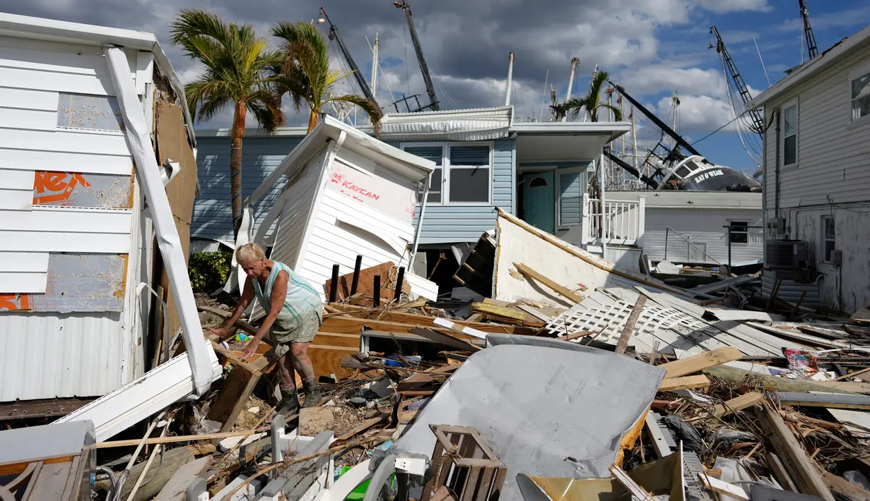 Kathy Hickey (70) dengan hati-hati mengambil jalan melalui puing-puing dari trailer yang hancur di taman rumah mobil tempat dia dan suaminya Bruce pasca terjadinya Badai Ian di Pulau San Carlos, Pantai Fort Myers, Florida, Rabu (5/10/2022). Tim pencari telah menyisir Pantai Fort Myers sepanjang 7 mil selama berhari-hari, mencari siapa pun yang masih membutuhkan bantuan. (AP Photo/Rebecca Blackwell)