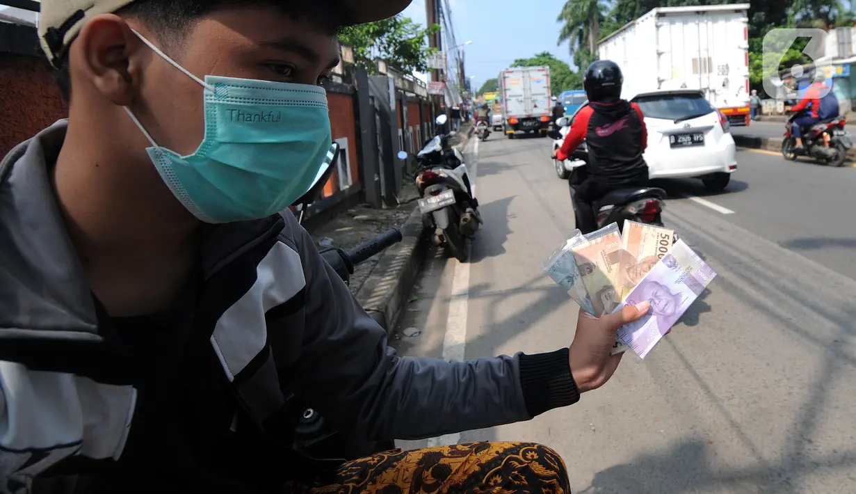 Penjual jasa penukaran uang menawarkan uang baru di kawasan Jalan Raya Parung, Bogor, Jawa Barat, Jumat  (7/5/2021). Penjual jasa yang marak jelang Idul Fitri tersebut banyak dijumpai di sejumlah jalan protokol. (merdeka.com/Arie Basuki)