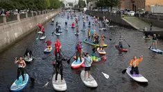 Sejumlah peserta mengenakan kostum mendayung papan Stand Up Paddle (SUP) di kanal Kryukov saat Surfing festival di St.Petersburg, Rusia (8/7). Dalam acara ini mereka mengenalkan olahraga air baru yang mirip Surfing. (AP Photo / Dmitri Lovetsky)
