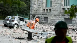 Petugas membersihkan puing-puing atap gedung yang runtuh sai gempa berkekuatan 5,6 magnitudo mengguncang Tirana, Albania (21/9/2019). Menurut lembaga survei Amerika Serikat, titik pusat gempa berada dekat Durres, kurang dari 40 kilometer sebelah barat ibu kota Tirana. (AFP Photo/Gent Shkullaku)