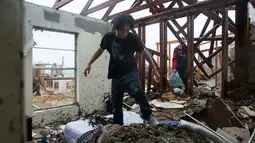 Dua orang pria mengumpulkan barang-barang yang masih tersisa dirumah mereka usai dilanda badai Harvey di Rockport, Texas (26/8). (Courtney Sacco/Corpus Christi Caller-Times via AP)
