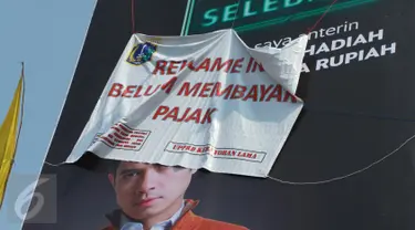 Sebuah reklame bergambar Dude Harlino tertutup spanduk di Kawasan Kebayoran Lama, Jakarta, Kamis (23/2). Reklame tersebut terkena razia oleh Satpol PP dan Dinas BP2T karena belum membayar pajak. (Liputan6.com/Gempur M Surya)
