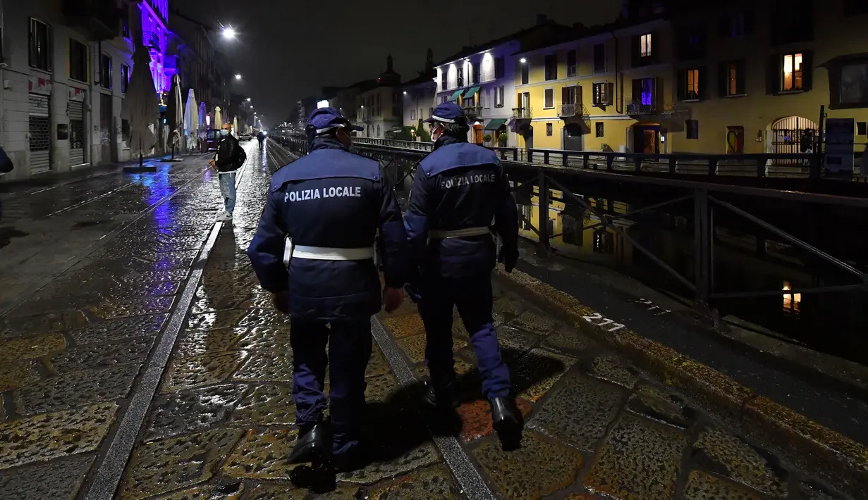 JAM MALAM DI ITALIA: Polisi berpatroli di sebuah jalan di tengah lonjakan infeksi coronavirus baru di Milan, Italia (22/10/2020). Jam malam diberlakukan terhadap lebih dari 21,7 juta warga Italia, yang mencakup sepertiga dari populasi negara itu di tengah lonjakan COVID-19. (Xinhua/Daniele Mascolo)