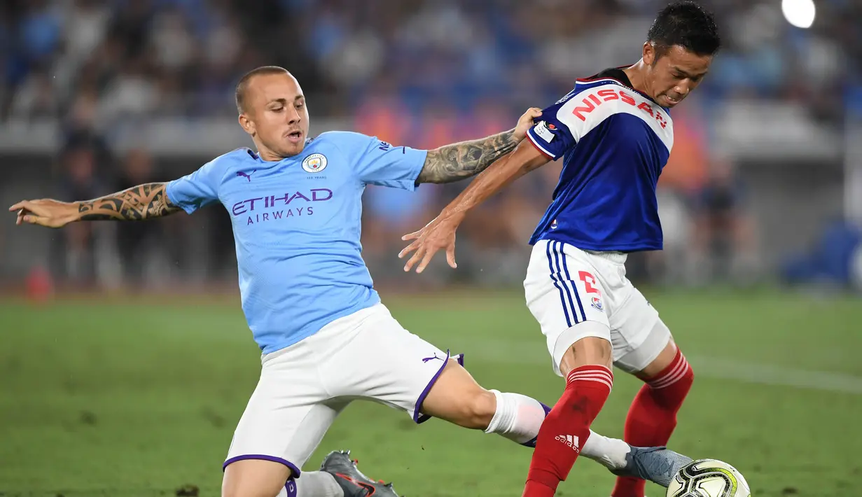 Bek Manchester City, Angelino, berebut bola dengan gelandang Yokohama Marinos, Takuya Kida, pada laga pramusim di Stadion Yokohama, Jepang, Sabtu (27/7). Yokohama kalah 1-3 dari City. (AFP/Charly Triballeau)