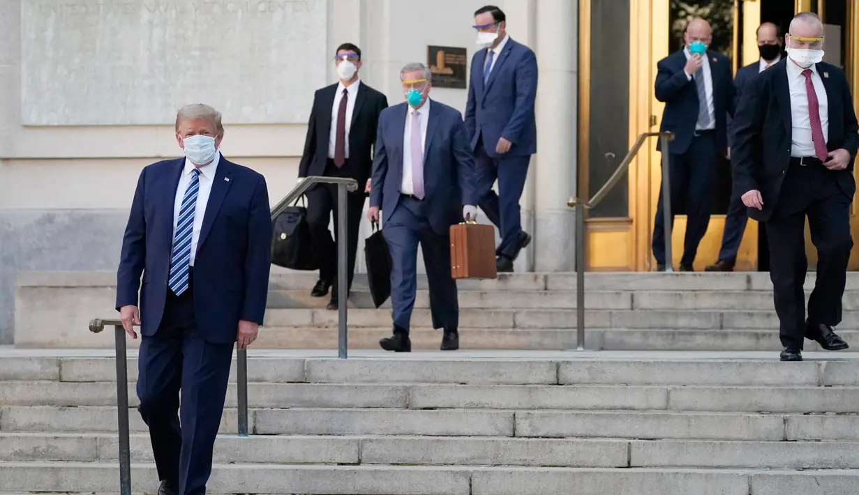 Presiden AS Donald Trump (Kiri) keluar dari Walter Reed National Military Medical Center di Bethesda, Maryland pada Senin (5/10/2020). Trump meninggalkan rumah sakit tempat dia dirawat karena Covid-19 dan langsung kembali ke Gedung Putih yang sedang menjadi kluster infeksi baru (AP Photo/Evan Vucci)