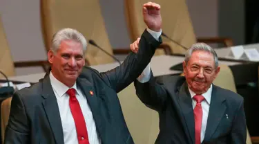 Presiden baru Kuba Miguel Díaz-Canel (kiri) dan Presiden Kuba Raul Castro mengangkat tangan mereka di Majelis Nasional, Havana, Kamis (19/4). Raul Castro mengumumkan Wakil Presiden Miguel Diaz-Canel sebagai penggantinya. (Alexandre Meneghini/Pool via AP)