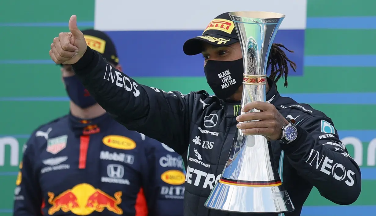 Pembalap Mercedes Lewis Hamilton memegang trofi saat merayakan kemenangannya pada F1 GP Eifel di Nuerburgring, Nuerburg, Jerman, Minggu (11/10/2020). Hamilton dengan 91 kemenangannya menyamai legenda F1 Michael Schumacher. (Ronald Wittek, Pool via AP)