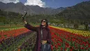 Seorang turis berswafoto menggunakan ponsel di Tulip Garden yang diklaim terbesar di Asia, di Srinagar, India pada Rabu (5/4/2023). (Photo by TAUSEEF MUSTAFA / AFP)