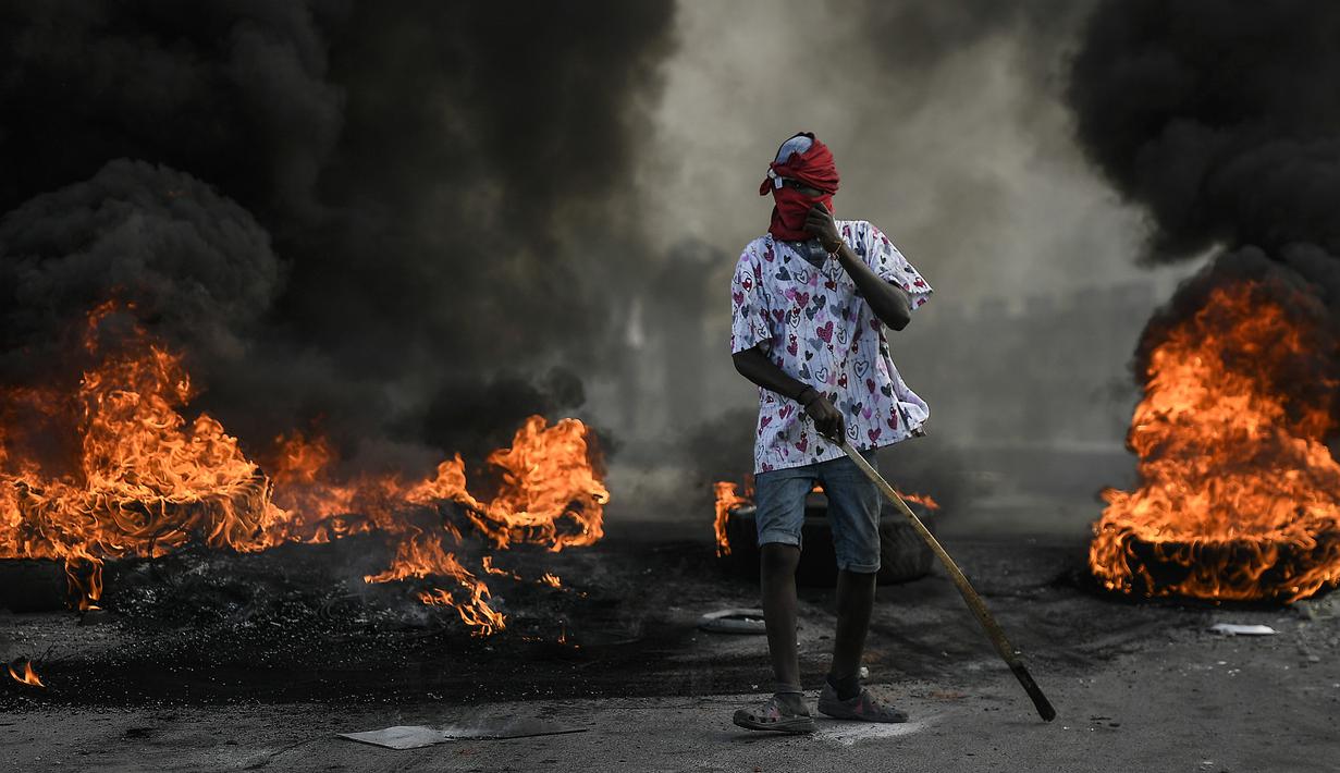 Demonstran berdiri dekat kobaran api saat menuntut keadilan atas pembunuhan Presiden Haiti Jovenel Moise di Cap-Haitien, Haiti, Kamis (22/7/2021). Demonstrasi menuntut keadilan atas pembunuhan Presiden Haiti Jovenel Moise terus berlanjut dan menimbulkan kerusuhan. (AP Photo/Matias Delacroix)