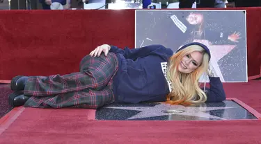 Penyanyi Avril Lavigne berpose di atas bintang barunya di Hollywood Walk of Fame setelah upacara  penghargaan untuknya, di Los Angeles, Rabu (31/8/2022). Avril Lavigne mendapat bintang ke-2.731 di Hollywood Walk of Fame. (Photo by Richard Shotwell/Invision/AP)