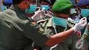 Seorang anggota dari Tim Gabungan SAR TNI membantu rekannya memakai masker saat bersiap menerima 4 jenazah penumpang AirAsia QZ8501, Surabaya, Kamis (1/1/2015). (Liputan6.com/Johan Tallo)