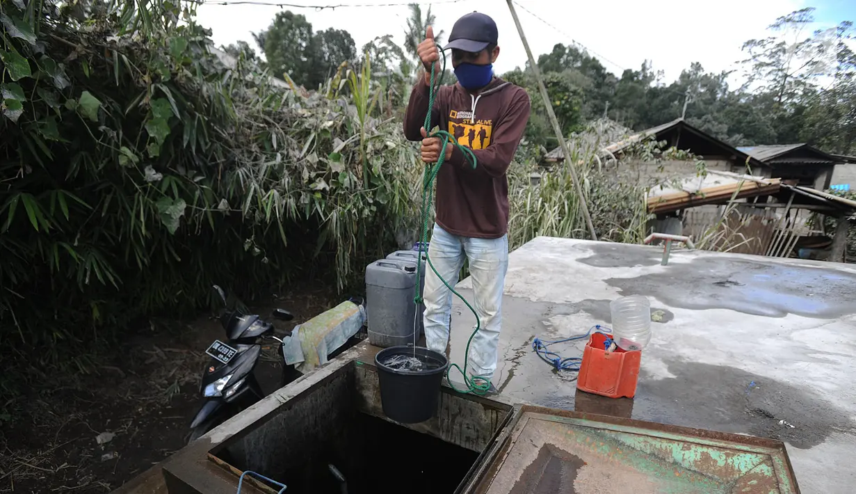 Warga mengenakan masker saat mengambil air di Desa Pempatan, Karangasem, Bali, Sabtu (30/6). Abu vulkanik erupsi Gunung Agung menyelimuti rumah dan kebun warga di sisi barat laut Gunung Agung. (Merdeka.com/Arie Basuki)