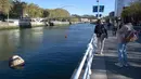Dua wanita mengambil gambar patung Bihar karya seniman hiperrealis asal Meksiko Ruben Orozco terendam di Sungai Nervion, Kota Bilbao, Basque, Spanyol, 14 Oktober 2021. Bihar diambil dari kata dalam bahasa Basque yang artinya 'besok'. (ANDER GILLENEA/AFP)