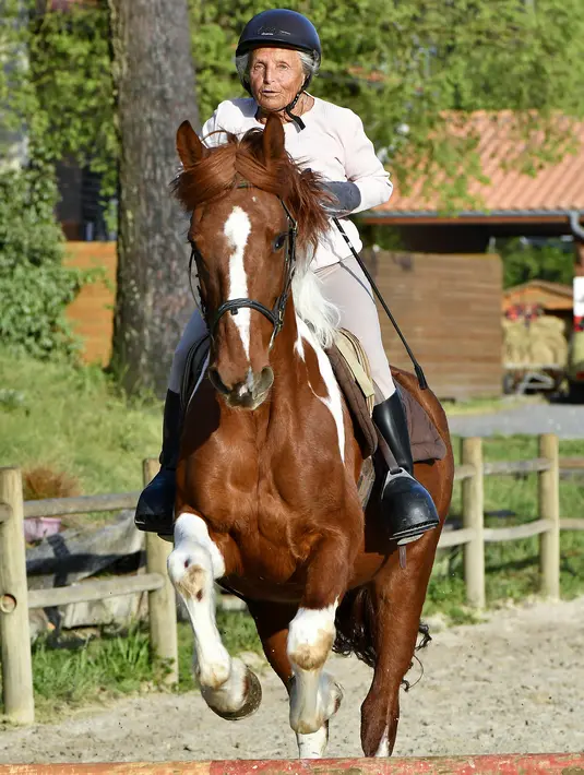 Aksi Nicole de Villeneuve (89) saat berlatih berkuda selama sesi pelatihan di Arcachon, Prancis (24/4). Seorang wanita cantik dengan mata hijau-biru mengatakan "Obatku adalah kuda, aku lupa segalanya,". (AFP Photo/Georges Gobet)