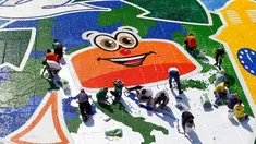 Sejumlah relawan membuat mosaik raksasa dari 100 ton limbah tutup botol dalam acara "A Bottle Cap for Handicap" di kota Novi Sad, Serbia, Sabtu (30/9). Pembuatan mosaik berukuran 621 meter persegi tersebut melibatkan 300 relawan. (AP/Darko Vojinovic)