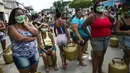 Warga memakai masker saat antre membeli gas murah dari Petrobrás Oil Tankers Union di favela Vila Vintem, Rio de Janeiro, Brasil, Jumat (12/3/2021). Kegiatan ini sebagai kampanye solidaritas untuk memperingati Hari Perjuangan Nasional Pertahanan Perusahaan Milik Negara. (AP Photo/Bruna Prado)