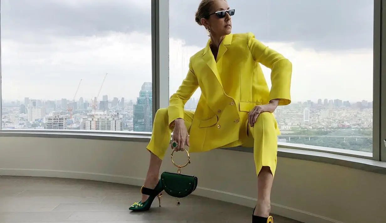 Inspirasi tampilan monokrom dari Celine Dion. Dalam foto ini, Celine Dion tampil dengan setelan blazer dan celana panjang berwarna kuning terang yang serasi. Foto: Instagram.