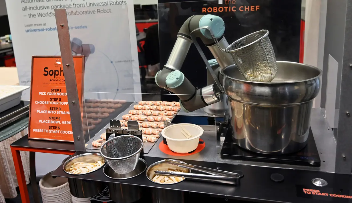 Robot koki bernama Sophie meracik semangkuk laksa saat demonstrasi memasak di Singapura pada 26 Juli 2019. Robot koki ini bisa merebus mie, menambahkan udang, dan menuangkan sup ke sebuah mangkuk. (Roslan RAHMAN / AFP)