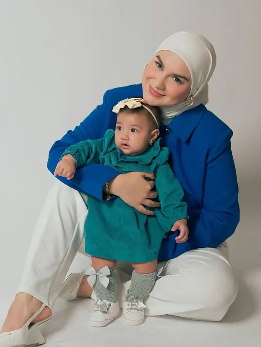 Irish Bella photoshoot dengan anak keduanya. Irish Bella tampil memesona dibalut kemeja biru, dipadunya dengan celana panjang dan hijab berwarna putih gading yang serasi. Sedang sang buah hati mengenakan dress lengan panjang yang cute, diberi tambahan aksesori bando pita dan kaus kaki abu-abu yang membungkus kaki mungilnya. Foto: Instagram.