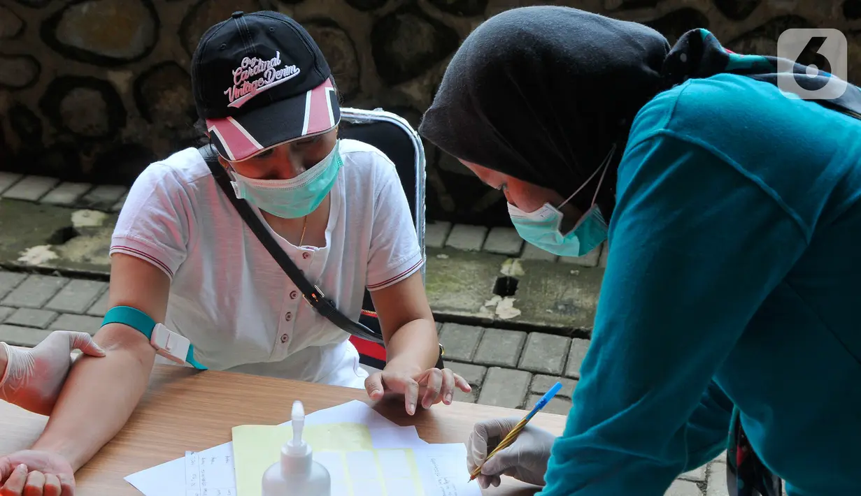 Petugas mencatat data seorang tenaga kesehatan medis saat melakukan rapid test pendektesian COVID-19 di Stadion Patriot Candrabhaga, Bekasi, Rabu (25/3/2020). Pemeriksaan hanya diperuntukan bagi tenaga medis seluruh puskesmas, dan rumah sakit yang ada di Kota Bekasi. (Liputan6.com/Herman Zakharia)