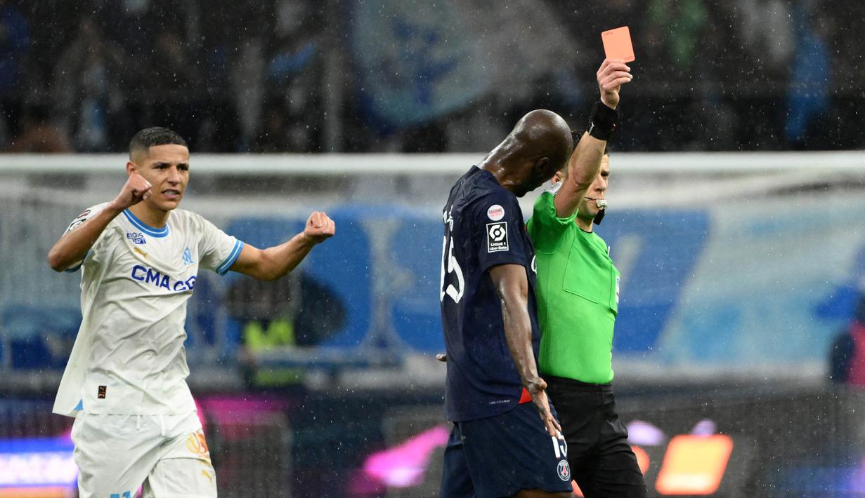 Pemain Paris Saint-Germain, Lucas Beraldo, mendpat kartu merah dari wasit saat melawan Marseille dalam duel pekan ke-27 Ligue 1 2023/2024 di Stade Velodrome, Senin (1/4/2024). (AFP/Christophe Simon)