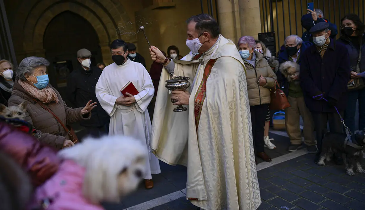 Pendeta Cesar Magana (tengah) memberkati hewan dan pemiliknya saat pesta Santo Antonius di Pamplona, Spanyol, 17 Januari 2022. Pesta santo pelindung hewan Spanyol ini dirayakan setiap tahun dan orang-orang membawa hewan peliharaan mereka ke gereja untuk diberkati. (AP Photo/Alvaro Barrientos)