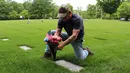 Veteran Marinir, Jim Segletes menempatkan bunga di makam keluarganya yang merupakan veteran Perang Dunia II saat Hari Pahlawan di AS (27/5). Hari libur ini diperingati dengan berkunjung ke makam pahlawan dan tugu peringatan. (AP Photo/Michael Rubinkam)