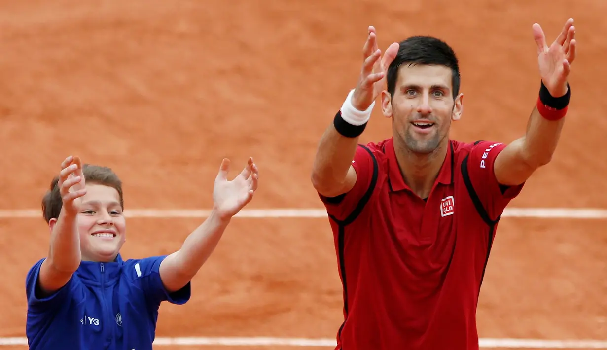 Petenis Serbia, Novak Djokovic, merayakan kemenangannya atas petenis Spanyol, Roberto Bautista Agut, bersama seorang ball boy dalam turamen tenis Prancis Terbuka 2016 di Roland Garros, Paris, (1/6/2016). (Reuters/Pascal Rossignol)