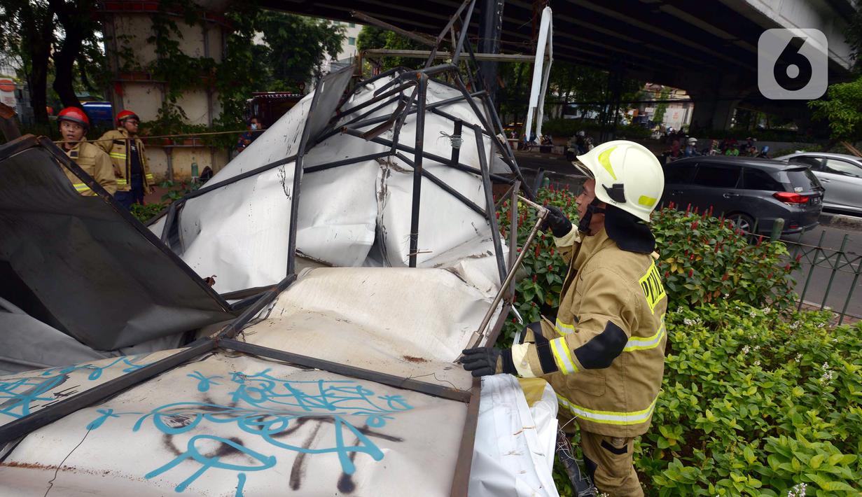 Petugas pemadam kebakaran memotong rangka reklame yang roboh di Jalan Soepomo, Jakarta, Sabtu (28/5/2022). Hujan disertai angin kencang pada pagi tadi membuat papan reklame roboh sehingga membuat kemacetan arus lalu lintas di jalan tersebut. (merdeka.com/Imam Buhori)