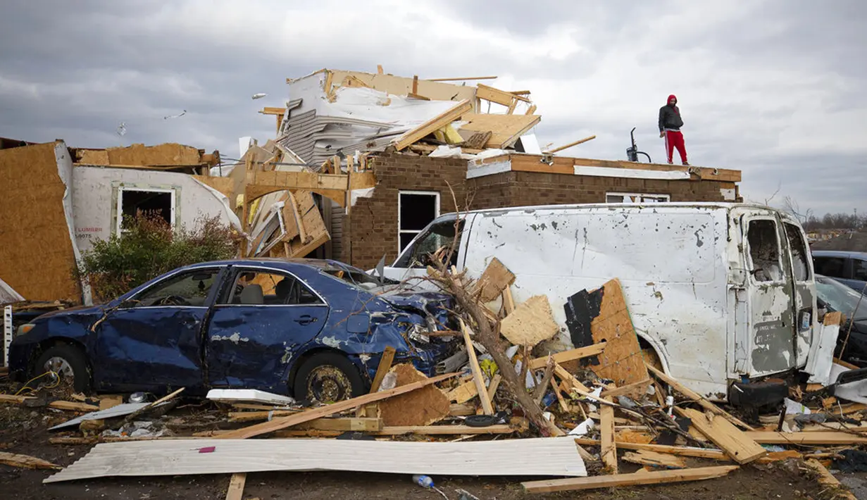 Redzo Beganovic berdiri di atas apartemennya yang hancur diterjang tornado di Bowling Green, Kentucky, Amerika Serikat, 11 Desember 2021. Presiden AS Joe Biden berjanji untuk mengunjungi wilayah yang rusak, tetapi tidak ingin "menghalangi penyelamatan dan pemulihan." (AP Photo/Michael Clubb)