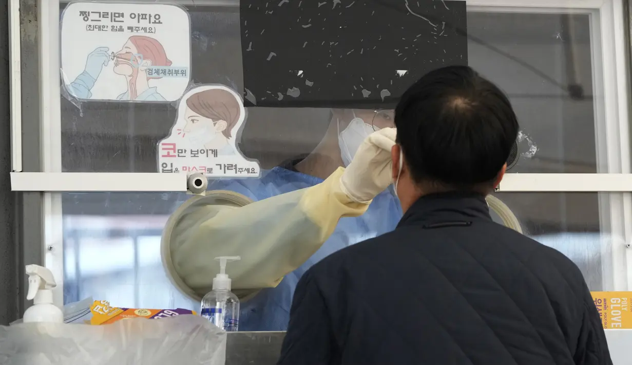 Petugas medis mengambil sampel hidung dari seorang pria di tempat pengujian COVID-19 darurat, Seoul, Korea Selatan, Rabu (24/11/2021). Kasus COVID-19 di Korea Selatan menembus 4.000 dalam sehari untuk pertama kalinya sejak dimulainya pandemi. (AP Photo/Ahn Young-joon)
