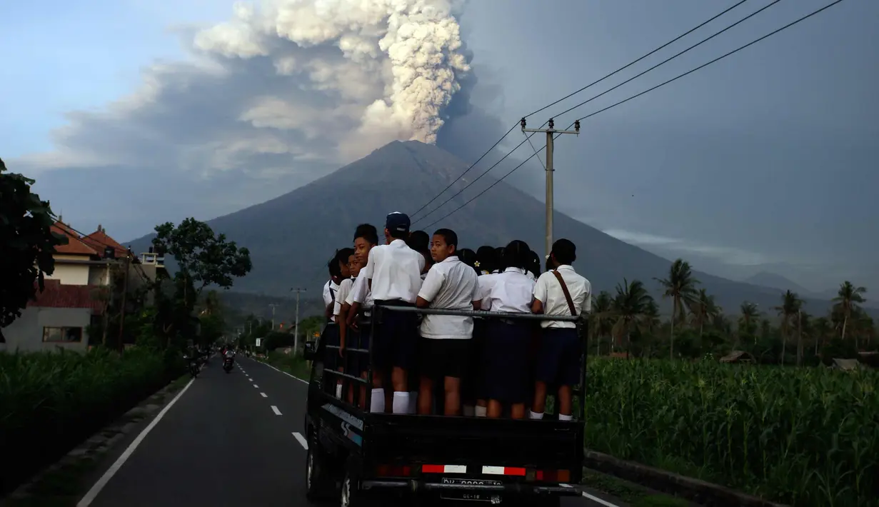 Para pelajar berdiri di sebuah mobil untuk pergi ke sekolah di tengah erupsi Gunung Agung di Karangasem, Bali, Selasa, (28/11). Erupsi Gunung Agung yang masih terjadi menyebabkan Bandara Ngurah Rai ditutup. (AP Photo/Firdia Lisnawati)