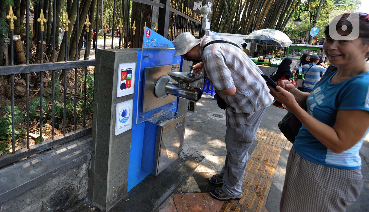 Wisatawan asing minum dari Keran Air Siap Minum (KASM) yang terpasang dekat Pintu 2 Kebun Raya Bogor, Jawa Barat, Minggu (6/10/2019). Pemkot Bogor melalui PDAM Tirta Pakuan membuat KASM di pendestrian Jalan Ir H Djuanda untuk menekan angka konsumsi botol dan gelas plastik. (merdeka.com/Arie Basuki)