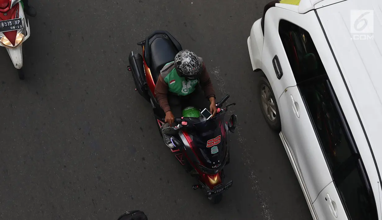 Pengendara sepeda motor mengoperasikan gawainya saat berkendara di Jakarta, Jumat (8/2). Polisi akan melakukan tindakan hukum berupa tilang kepada pengendara yang menggunakan GPS saat berkendara. (Liputan6.com/Immanuel Antonius)