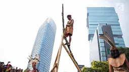 Penari berpakaian adat Dayak melakukan pertunjukan memanjat pohon manau berduri pada pawai budaya saat Car Free Day di kawasan Sudirman, Jakarta, Minggu (29/10). Kegiatan ini dikemas dengan nama Gelar Pesona Budaya Tabalong. (Liputan6.com/Faizal Fanani)