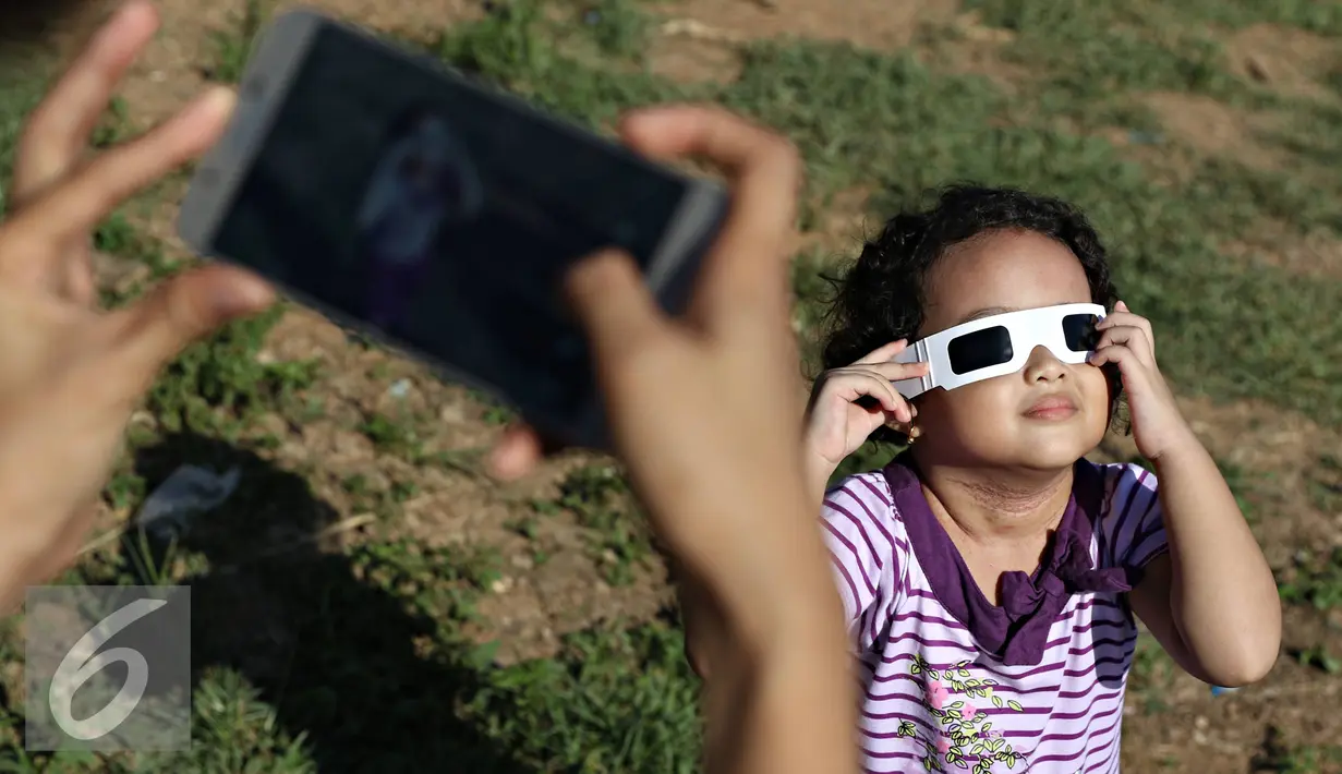 Seorang anak melihat proses gerhana matahari di Bukit Matantimali, Sigi, Sulteng, Rabu (9/3). Fenomena tersebut menjadi daya tarik tersendiri wisatawan untuk menyaksikan secara langsung di alam terbuka. (Liputan6.com/Immanuel Antonius)