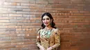 Anggun elegan Selvi Ananda mengenakan batik dalam balutan outfit modern. Sebuah dress lengan panjang dan pinggang yang ketat membalut tubuhnya dengan amat baik, memperlihatkan motif batik cokelat kekuningan. [Foto: Instagram/selvirakabuming]