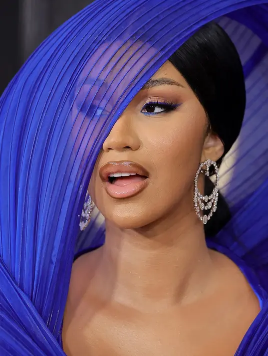 <p>Cardi B memadukan tampilan eyeliner dengan bibirnya. Eyeliner biru kobalt yang halus disesuaikan dengan bibir yang mengkilap, liner cokelat yang sengaja diperlihatkan. Belum lagi sanggulnya yang licin dan rambut berbelah samping yang membuat penampilannya semakin sempurna. Foto: Glamour</p>