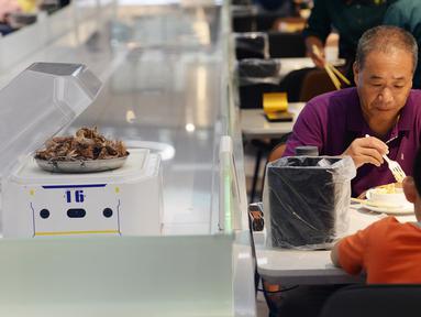 Pengunjung menunggu makanan yang akan diantarkan oleh robot di restoran Robot.He milik Alibaba di Shanghai, 30 Juli 2018. Robot pintar yang sebesar oven microwave bertugas menerima pesanan dan mengantarkan makanan di atas nampan kepada para tamu. (AFP)