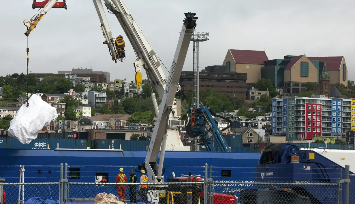 Foto-foto menunjukkan para kru kapal selam Titan menurunkan potongan-potongan besar kapal selam selam sepanjang 22 kaki di Newfoundland. (Paul Daly/The Canadian Press via AP)