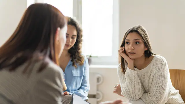 Seorang perempuan sedang menyimak penjelasan temannya sambil memegang dahu (Foto Dok: Freepik/freepik)