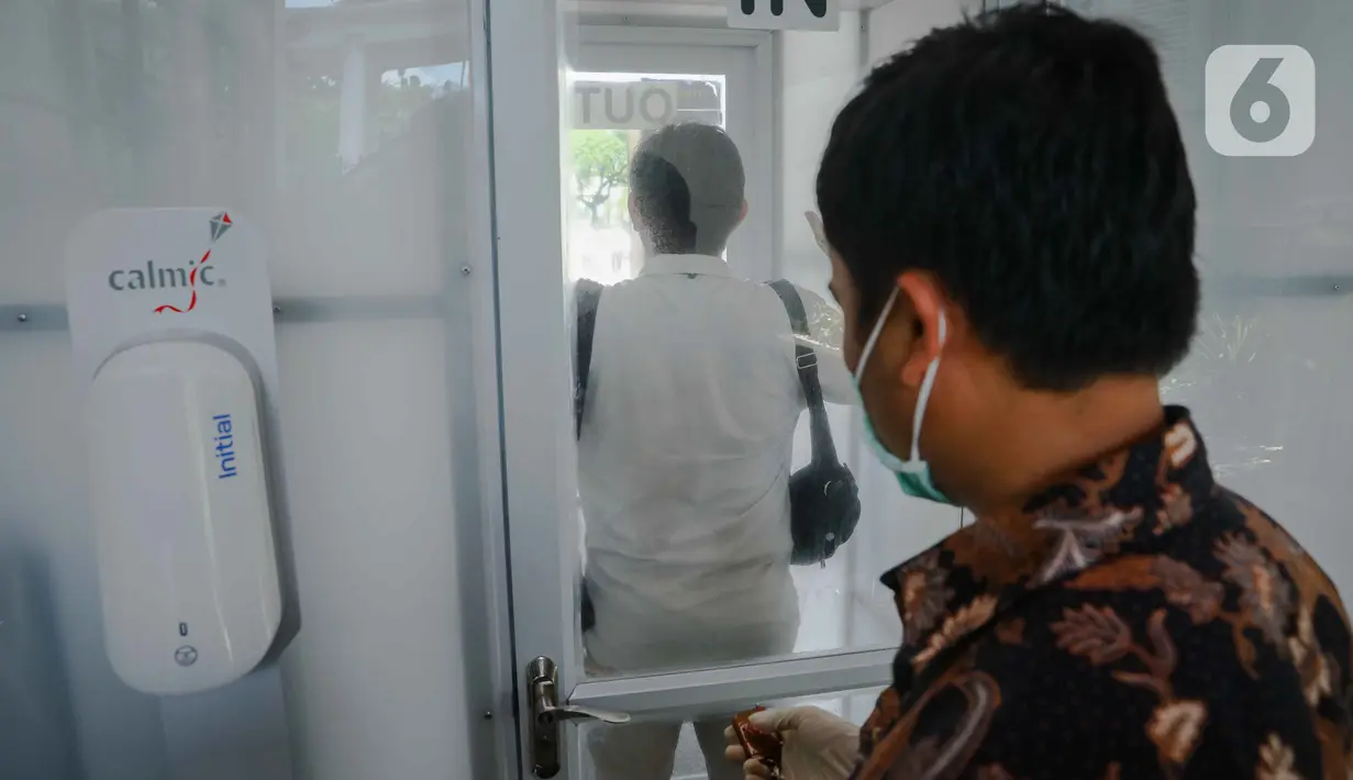 Pengunjung memasuki ruang disinfeksi  yang disiapkan di pintu masuk menuju kompleks Istana, Jakarta, Senin (16/3/2020). Pihak Istana Kepresidenan menyediakan ruang disinfeksi berbentuk kubus berwarna putih untuk mendeteksi tamunya yang terjangkit virus corona Covid-19. (Liputan6.com/Faizal Fanani)