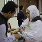 Panitia Penyelenggara Ibadah Haji (PPIH) memberikan gelang untuk calon jemaah haji kloter pertama di Asrama Haji, Jakarta, Sabtu (6/7/2019). Sebelum diberangkatkan, petugas mengecek kembali 385 calon jamaah untuk melakukan kelengkapan administrasi. (Liputan6.com/Faizal Fanani)