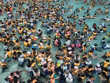 Wisatawan memadati water park yang dikenal dengan Caribbean Bay di Yongin, luar Seoul, Senin (6/8). Gelombang panas yang melanda Korea Selatan akhir-akhir ini membuat ratusan warga memenuhi kolam renang untuk mengurangi hawa panas. (Ed JONES/AFP)