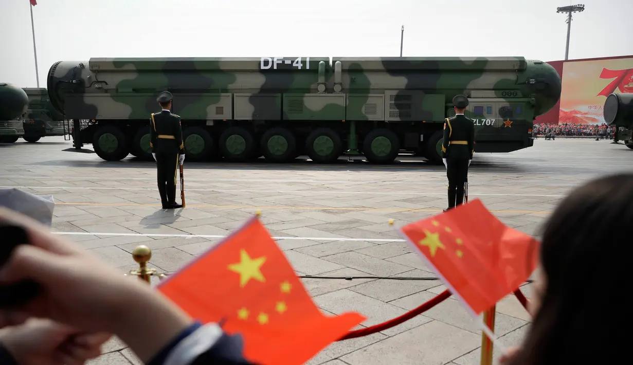 Warga mengibarkan bendera China saat kendaraan militer yang membawa Dongfeng-41 atau DF-41 melintas dalam parade militer di Beijing, 1 Oktober 2019. Rudal balistik antarbenua DF-41 menjadi sorotan pengamat dan ahli persenjataan dunia karena disebut dapat menjangkau wilayah AS. (AP/Mark Schiefelbein)