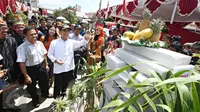 Menpan RB Yuddy Chrisnandi (topi) menunjuk sebuah monumen yang dibuat oleh para panitia TPS Kampung Pilkada RW 03 di Depok, Jawa Barat, Rabu (9/12). Menpan hadir ke TPS untuk melakukan pemantauan Pemilihan Umum yang aman.  (Liputan6.com/Immanuel Antonius)